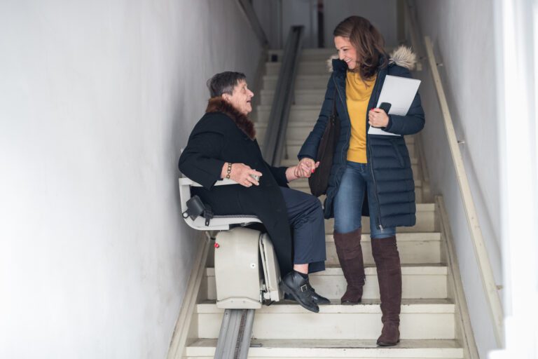 young woman helping older woman on stair lift