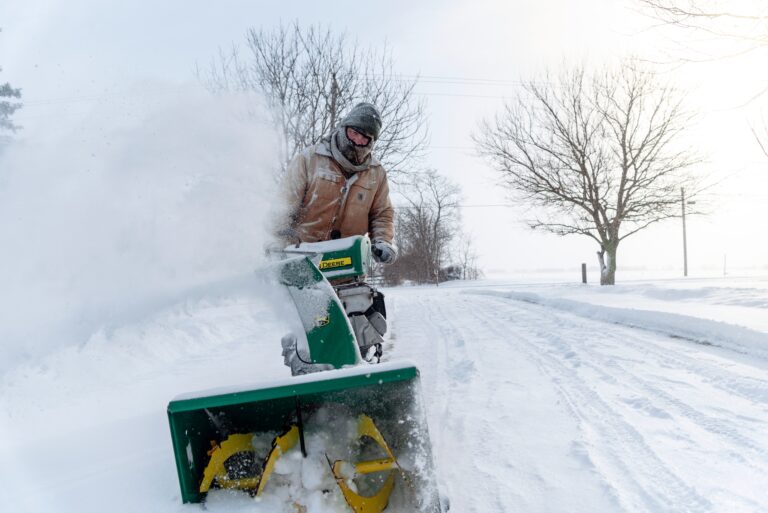 man using snow blower in a blizzard
