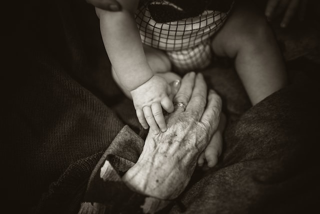 black and white photo of baby holding grandmother's hand